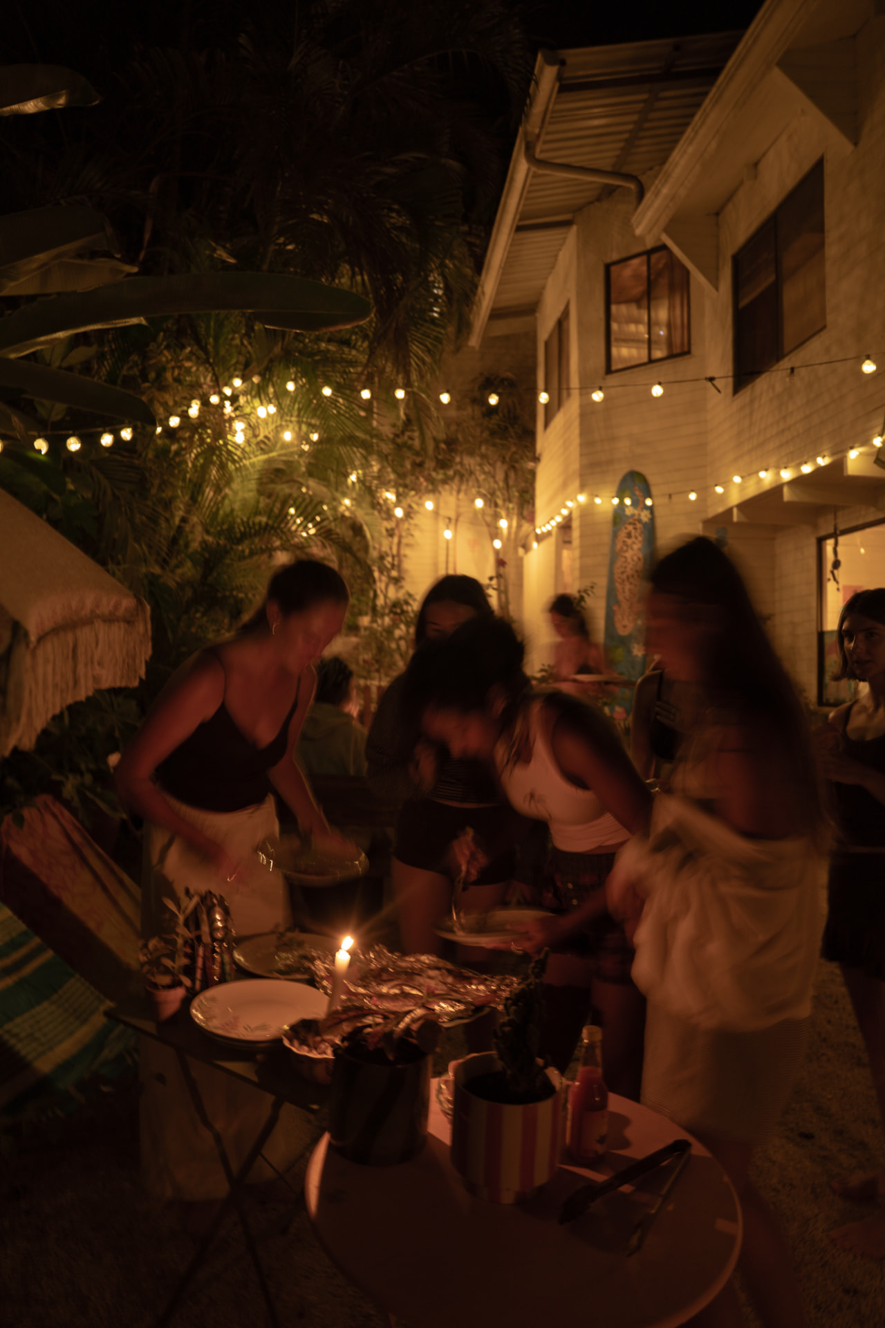 Friends sharing a candlelit dinner in the garden at night