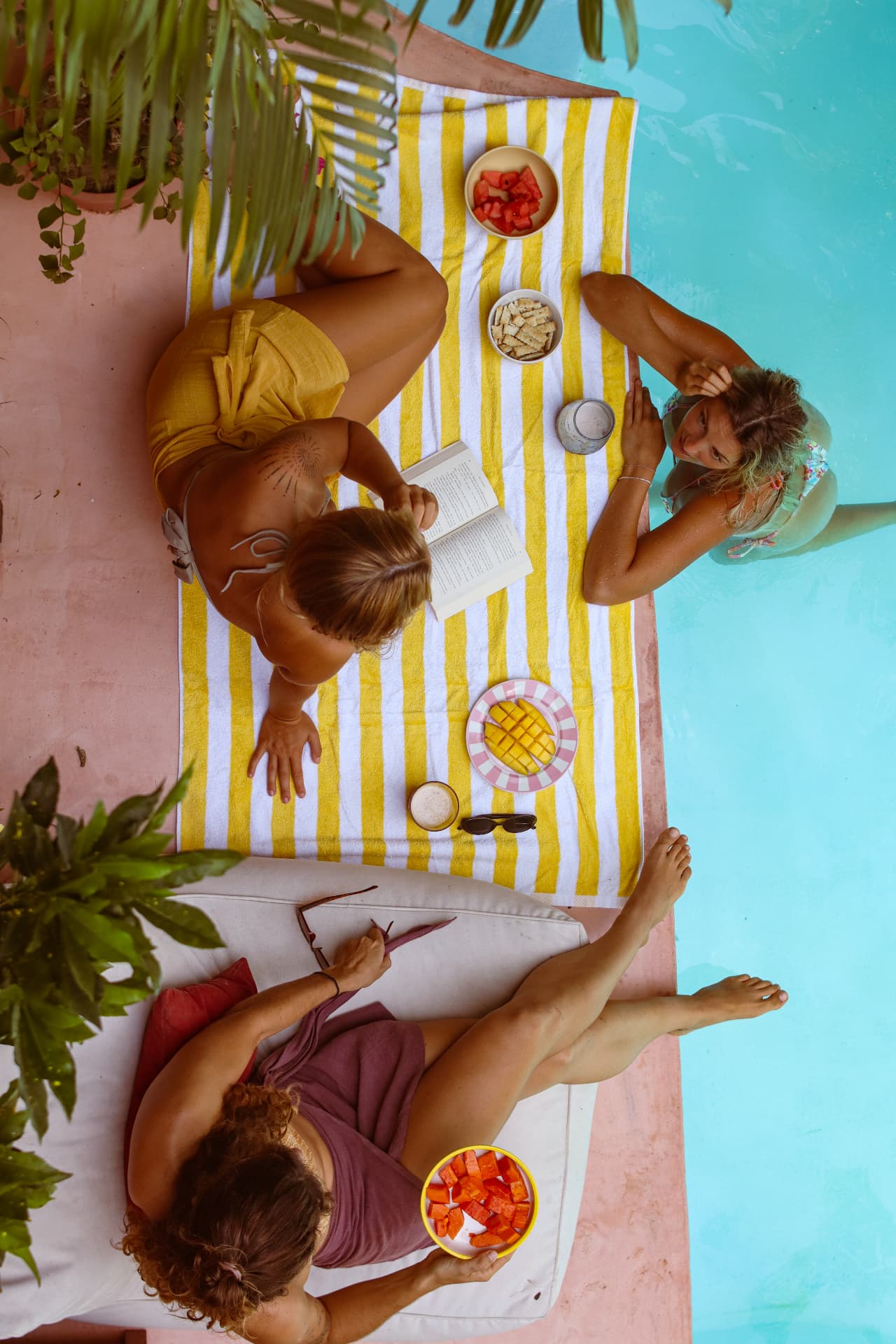 Friends sharing fruit and a book beside the pool