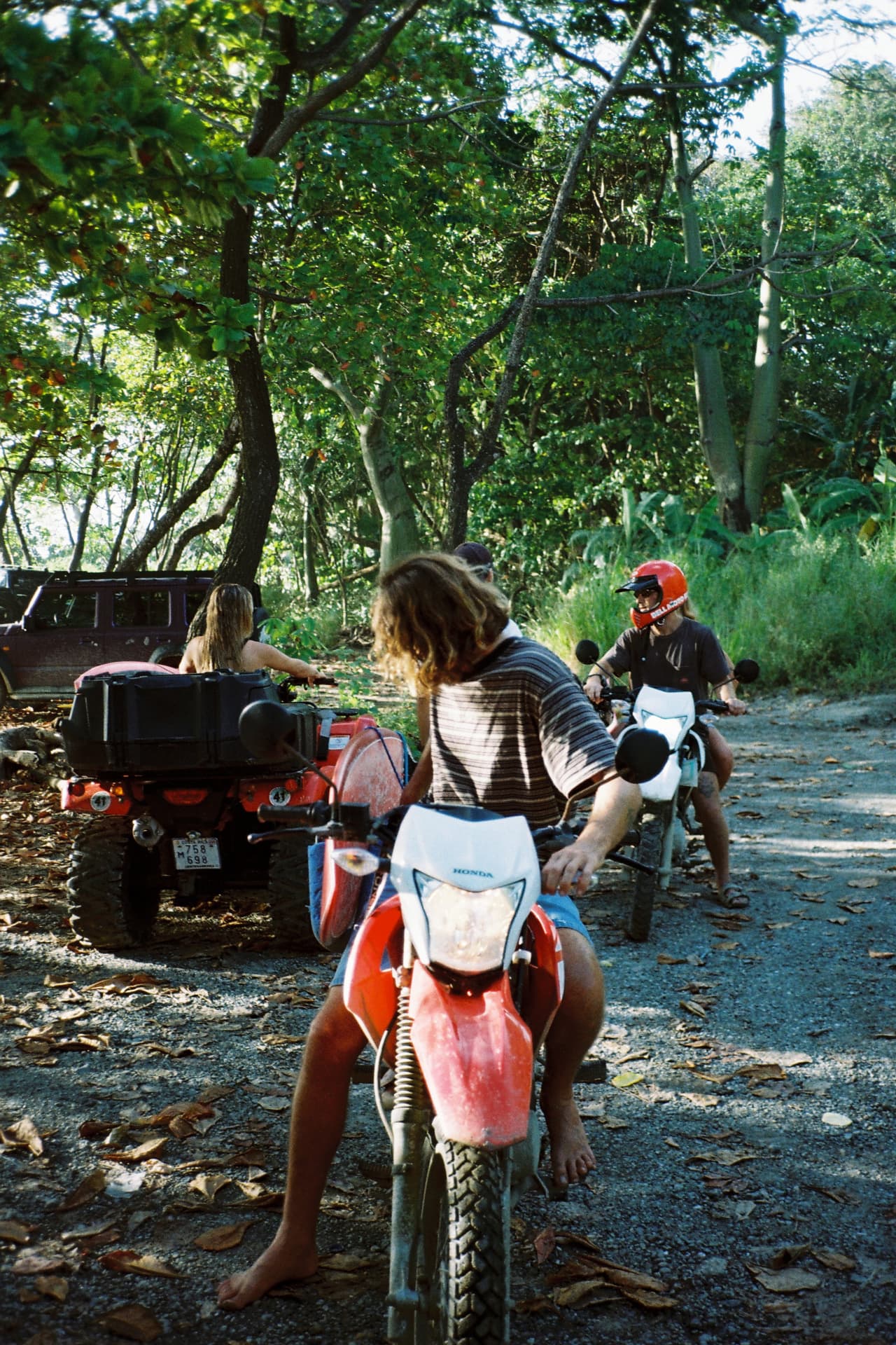Dirt bikes and ATVs parked under the jungle trees