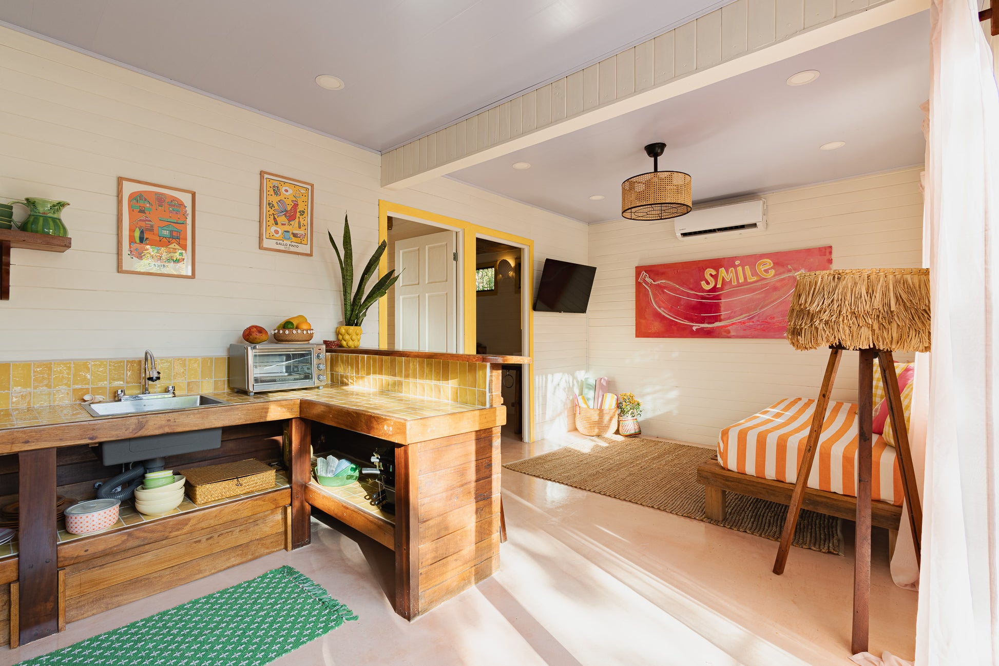 Apartment Piña — Kitchen and living room with sofa bed and "Smile" artwork