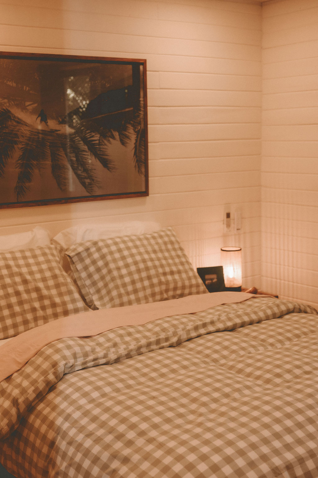Gingham-dressed bed with surf artwork