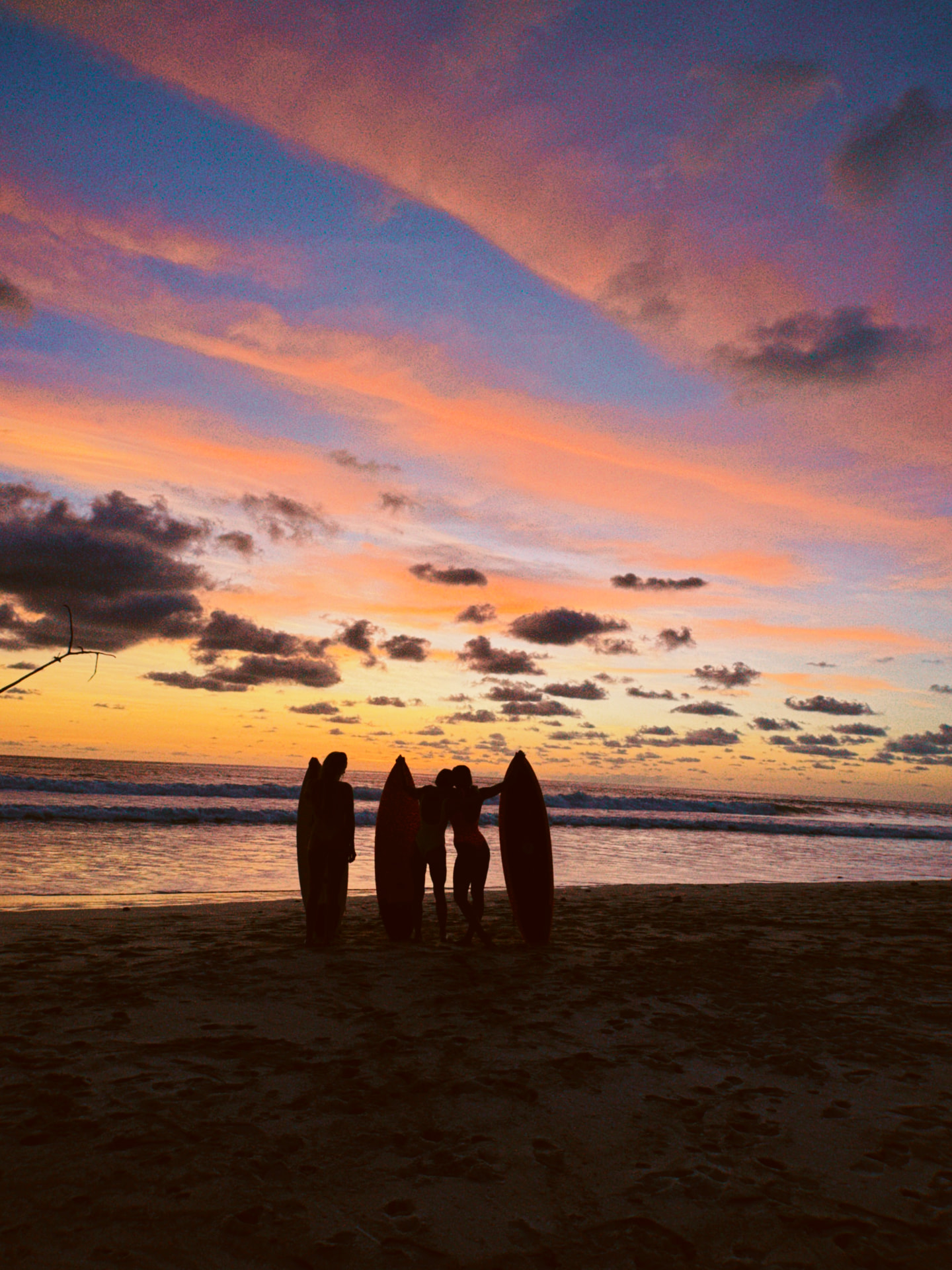 Surfers with their boards silhouetted against a colorful sunset