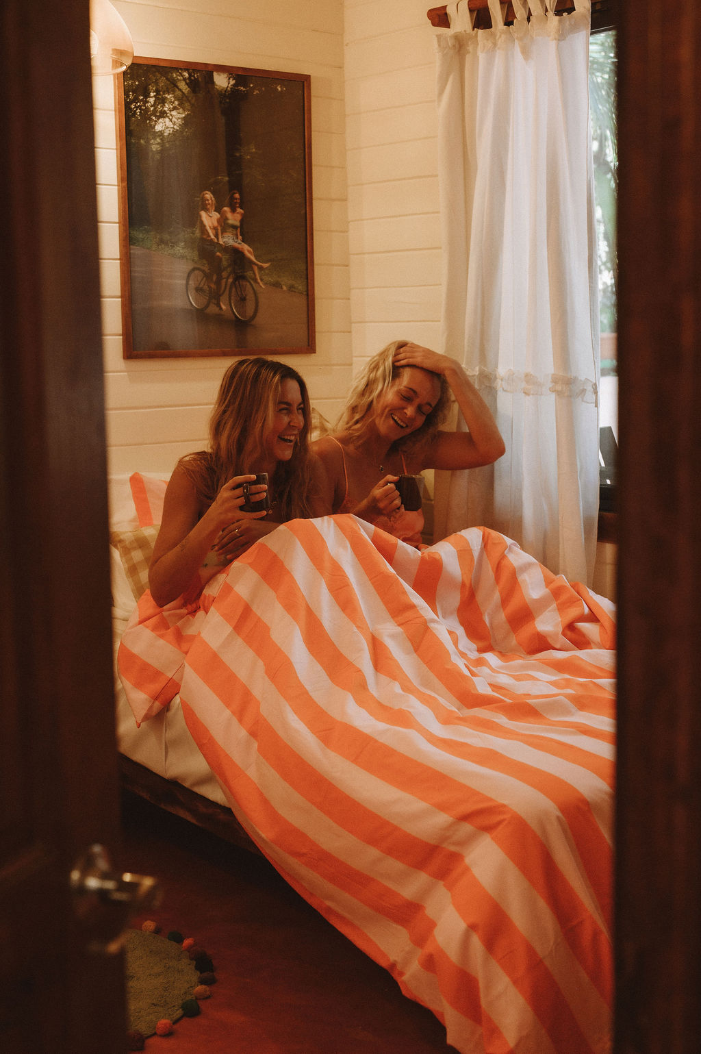 Friends laughing in bed with morning coffee