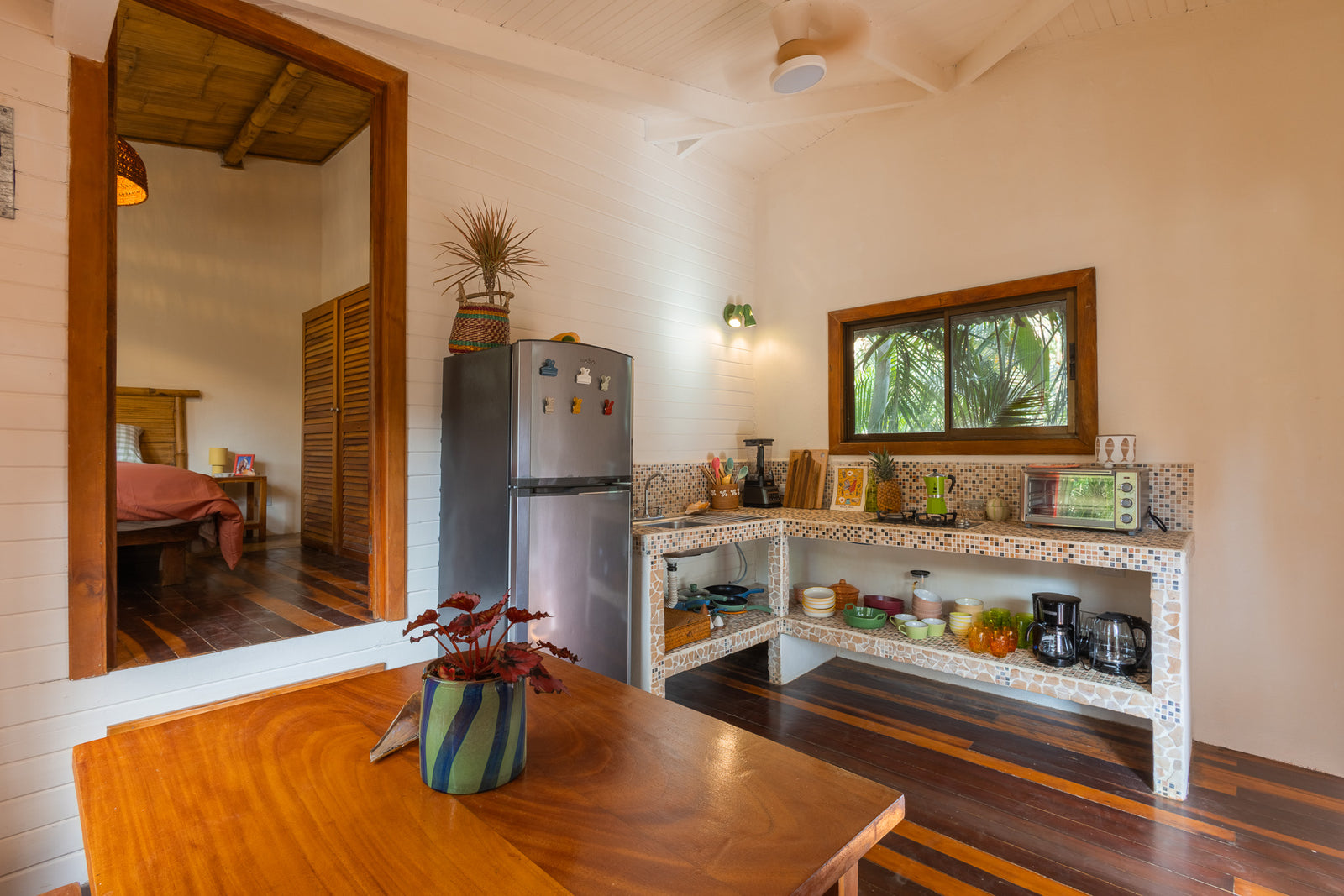 Apartment Sandía — Kitchen and dining area with wooden floors, bedroom beyond