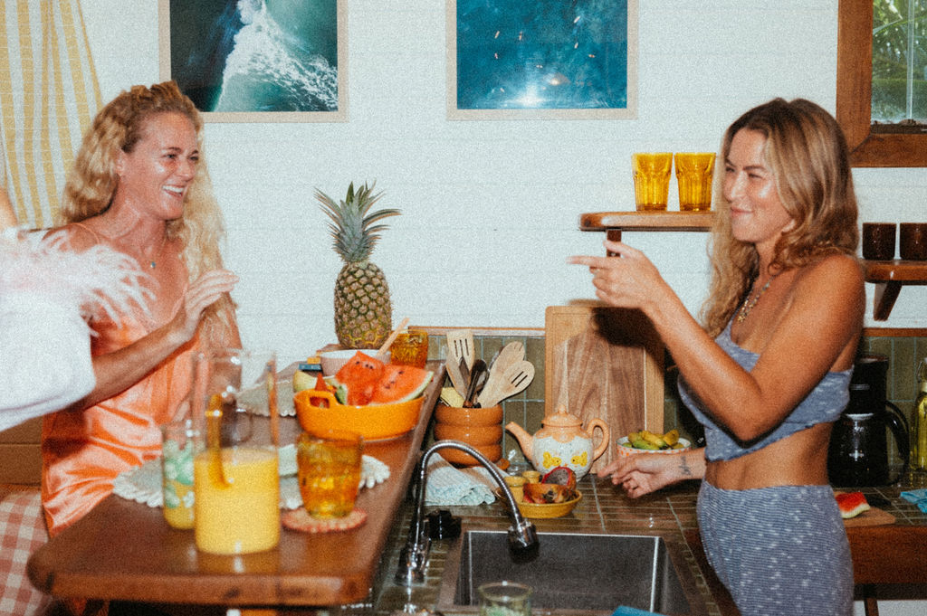 Friends laughing over fresh pineapple and juice in the kitchen